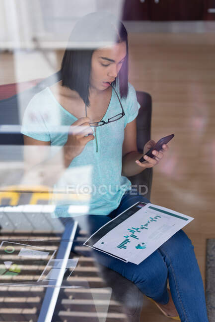 Mixed race transgender woman working at home talking on smartphone. staying at home in isolation during quarantine lockdown. — Stock Photo