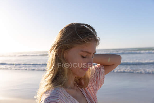 Кавказька жінка у пляжному покритті чіпляється за волосся на пляжі. Здоровий вільний час на відкритому повітрі біля моря. — стокове фото