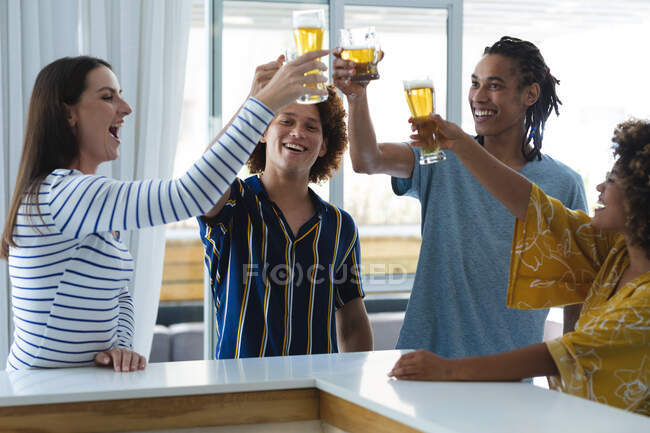 Diverse männliche und weibliche Kollegen heben an der Theke Biergläser. Freunde treffen sich und trinken an der Bar. — Stockfoto