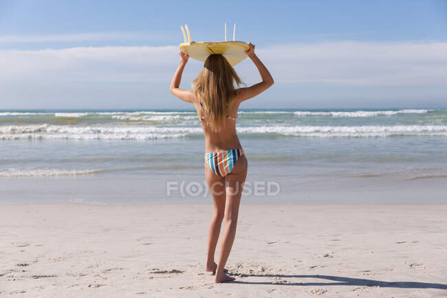 Кавказька жінка в бікіні носила серфінг на голові на пляжі. Здоровий вільний час на відкритому повітрі біля моря. — стокове фото