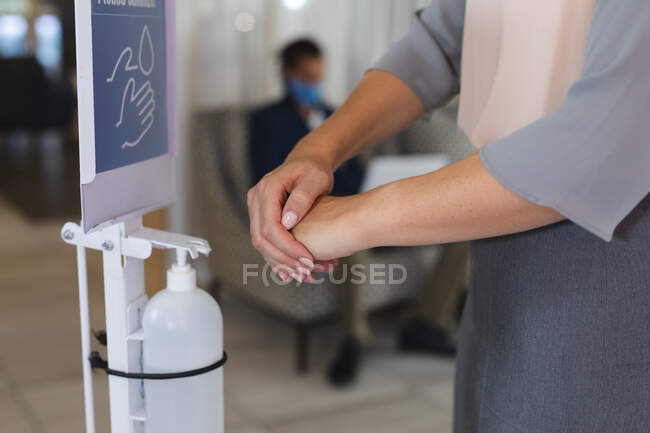 Milieu de la femme désinfectant les mains dans le hall de l'hôtel. hôtel de voyage d'affaires pendant la pandémie de coronavirus covid 19. — Photo de stock