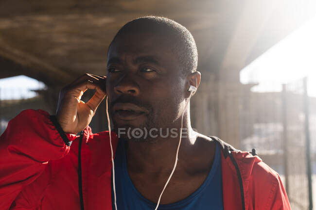 Портрет афроамериканського чоловіка, який займається фізичними вправами на відкритому повітрі, носить навушники, слухає музику. здорове тренування на відкритому повітрі. — стокове фото