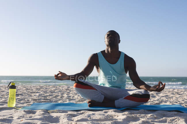 African american man exercising outdoors, practicing yoga, meditating on beach. healthy outdoor lifestyle fitness training. — Stock Photo