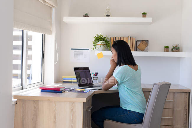 Mixed race gender fluid man working at home using laptop. staying at home in isolation during quarantine lockdown. — Stock Photo