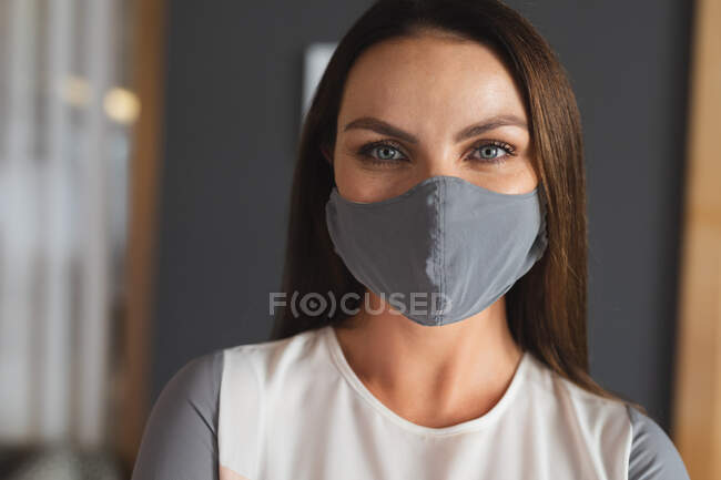 Retrato de una mujer caucásica con mascarilla en el vestíbulo del hotel. viaje de negocios hotel durante coronavirus covid 19 pandemia. - foto de stock