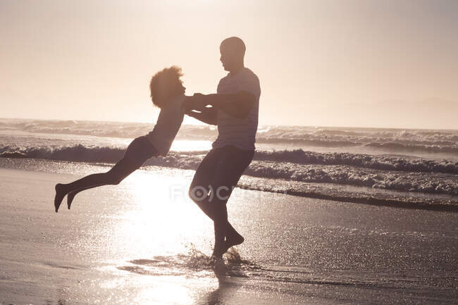 Afrikanisch-amerikanischer Vater und Tochter beim Spinning am Strand. Familienfreizeit im Freien am Meer. — Stockfoto