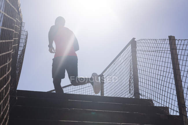 Hombre afroamericano haciendo ejercicio, subiendo las escaleras en un día soleado. estilo de vida al aire libre saludable entrenamiento fitness. - foto de stock
