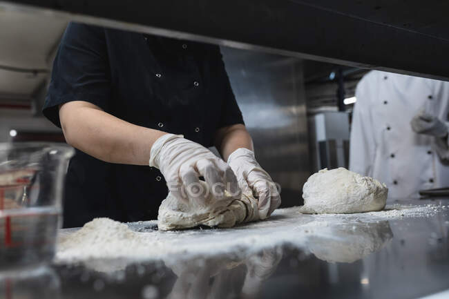 Мидсекция профессионального шеф-повара, готовящего тесто в гигиенических перчатках. работа на кухне ресторана. — стоковое фото