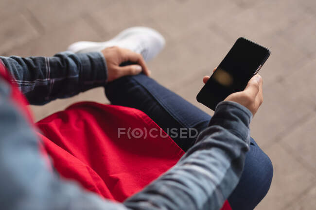 Mid section of male barista sitting on bench using smartphone. independent small business in a city. — Stock Photo
