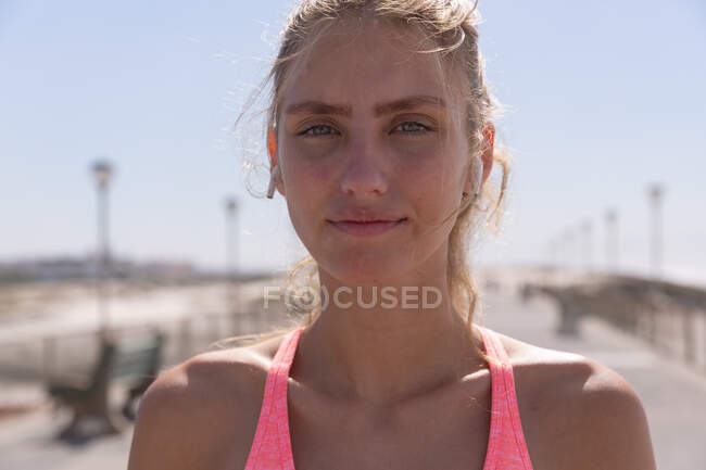 Portrait of caucasian woman exercising looking at camera on a promenade by the beach. healthy outdoor leisure time by the sea. — Stock Photo