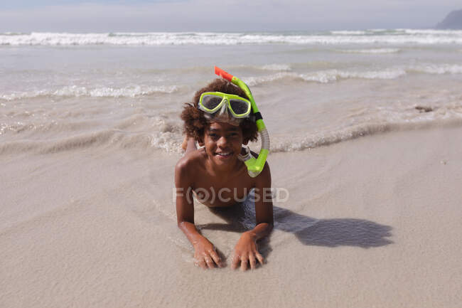 Афріканський американець, одягнений в аквалангістську маску, лежить на пляжі і посміхається. Здоровий вільний час на відкритому повітрі біля моря. — стокове фото