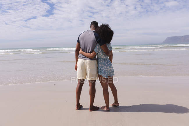 African american couple standing and embracing at the beach. healthy outdoor leisure time by the sea. — Stock Photo