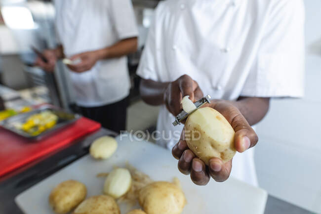 Midsection of professional chefs preparing vegetables wearing. working in a busy restaurant kitchen. — Stock Photo