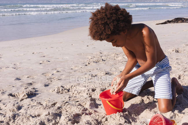 Afrikanischer amerikanischer Junge beim Spielen mit Sand am Strand. Familienfreizeit im Freien am Meer. — Stockfoto