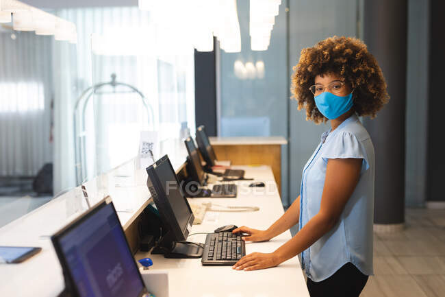 Portrait of woman wearing face mask working as receptionist in hotel. business travel hotel during coronavirus covid 19 pandemic. — Stock Photo