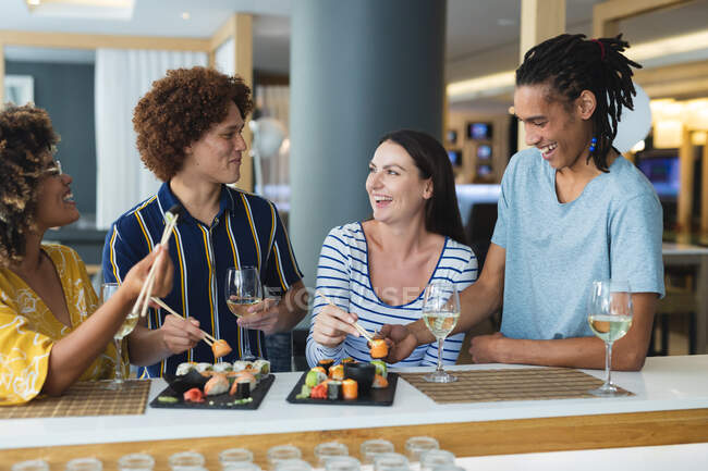 Diverse group of male and female colleagues having wine and sushi at bar. friends socialising and drinking at bar. — Stock Photo