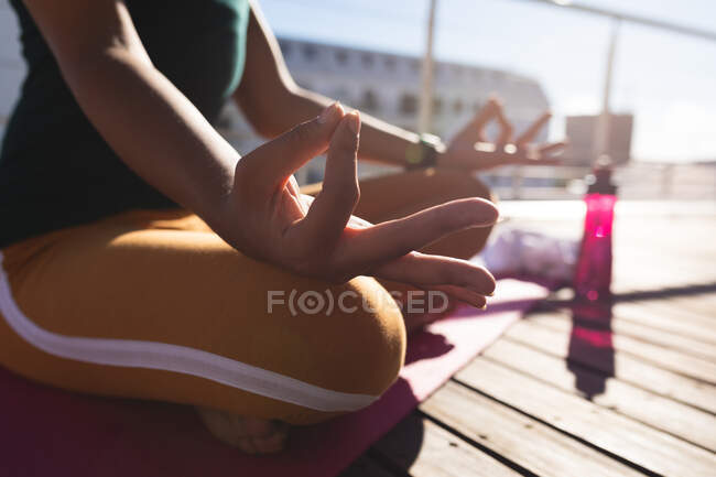 Mittelteil einer Transgender-Frau, die Yoga-Meditation auf einer Dachterrasse in der Sonne praktiziert. Isolationshaft während der Quarantäne. — Stockfoto