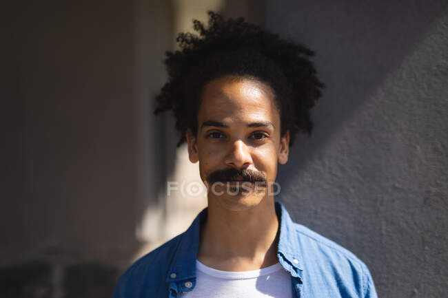 Portrait d'un homme de race mixte avec une moustache regardant vers la caméra. mode de vie urbain vert, dans la ville. — Photo de stock