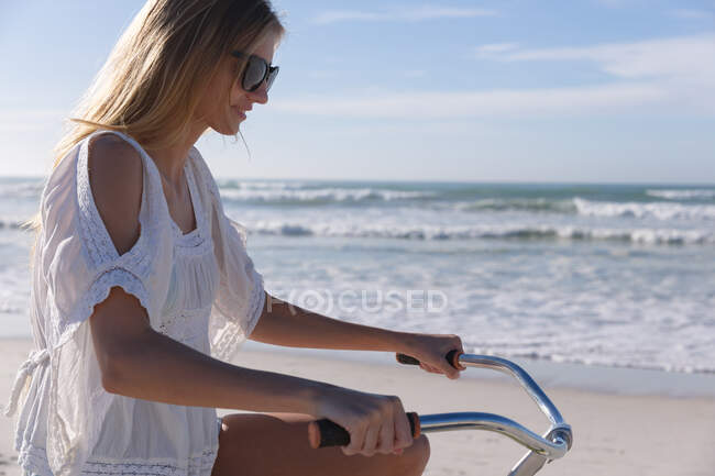Mulher branca a andar de bicicleta na praia. tempo de lazer ao ar livre saudável pelo mar. — Fotografia de Stock