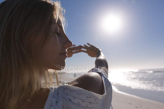 Кавказька жінка стоїть і розтягується на пляжі. Здоровий вільний час на відкритому повітрі біля моря. — стокове фото