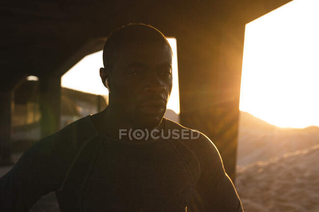 Retrato do homem afro-americano exercitando-se ao ar livre sob ponte ao pôr-do-sol. treinamento de fitness ao ar livre saudável. — Fotografia de Stock