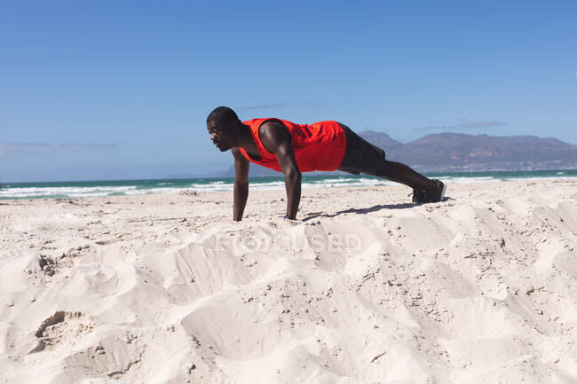 Cansado afro-americano exercitando-se na praia no dia ensolarado. treinamento de fitness ao ar livre saudável. — Fotografia de Stock