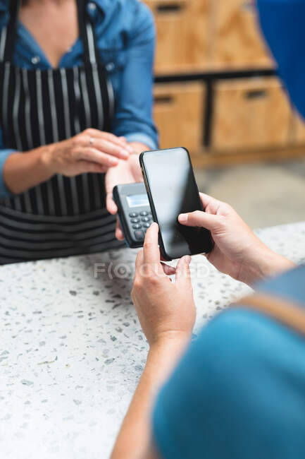 Midsection of caucasian woman making contactless phone payment over counter at gym. fitness and leisure time at gym during coronavirus covid 19 pandemic. — Stock Photo