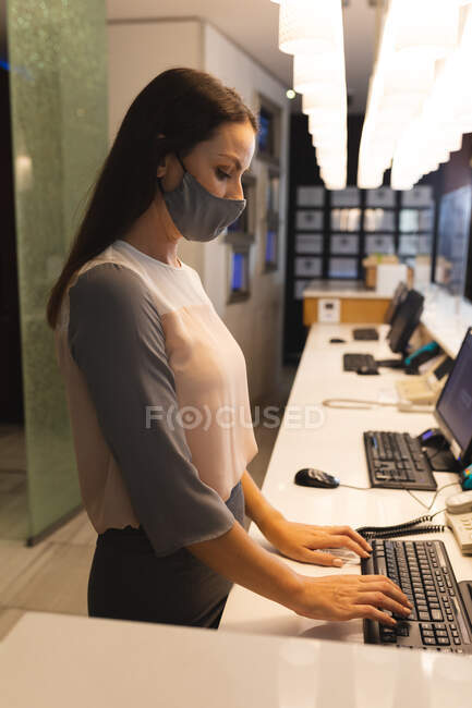 Portrait of caucasian woman wearing face mask working in reception in hotel. business travel hotel during coronavirus covid 19 pandemic. — Stock Photo