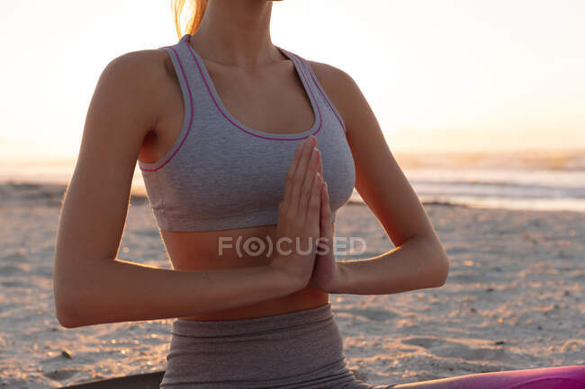 Seção média de mulher meditando e praticando ioga na praia. fitness ioga e conceito de estilo de vida saudável — Fotografia de Stock