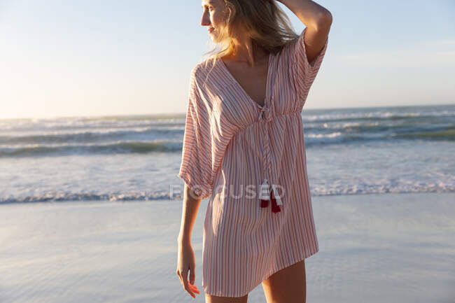 Caucasian woman wearing beach cover up having fun at the beach. healthy outdoor leisure time by the sea. — Photo de stock