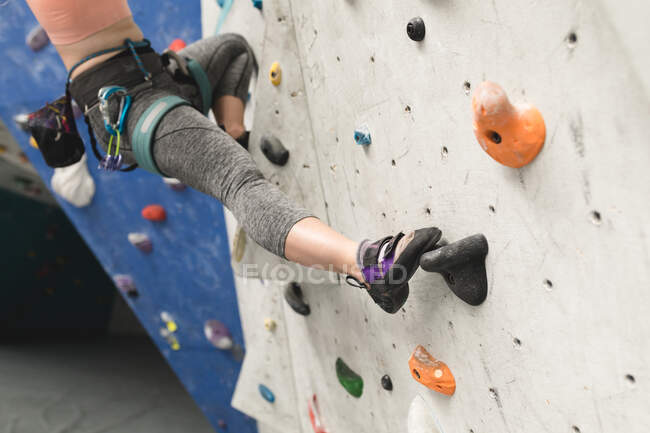Secção média de mulher a subir uma parede no ginásio de escalada interior. fitness e tempo de lazer no ginásio. — Fotografia de Stock