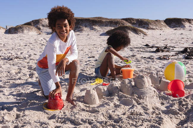 African american children having fun playing with sand at the beach. family outdoor leisure time by the sea. — Stock Photo