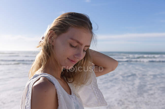 Lächelnde Kaukasierin, die mit geschlossenen Augen am Strand steht. gesunde Freizeit im Freien am Meer. — Stockfoto