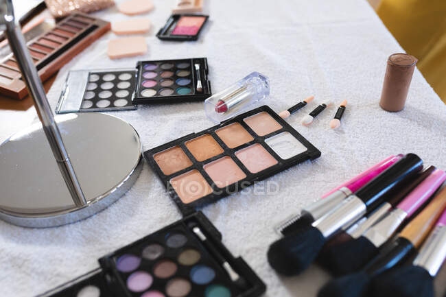 Selection of makeup brushes, sponges, eye shadows, lipstick,face powders and a mirror on a table top. part of a woman's makeup set. — Stock Photo