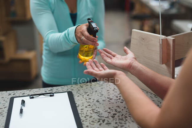 Milieu de la réceptionniste féminine désinfectant les mains d'une cliente sur le comptoir à la salle de gym. fitness et temps libre à la salle de gym pendant coronavirus covid 19 pandémie. — Photo de stock