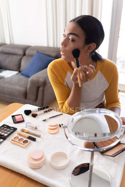 Mixed race transgender woman putting on makeup and talking. staying at home in isolation during quarantine lockdown. — Stock Photo