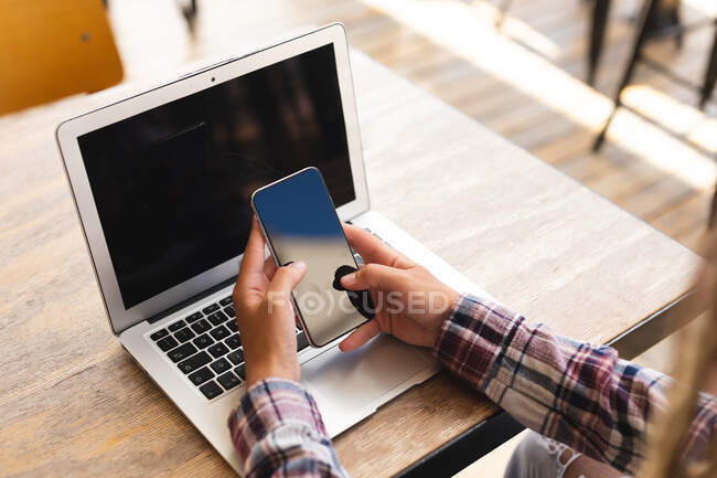 Metà sezione di uomo seduto a tavola fuori caffè con computer portatile utilizzando smartphone. nomade digitale, in giro per la città. — Foto stock