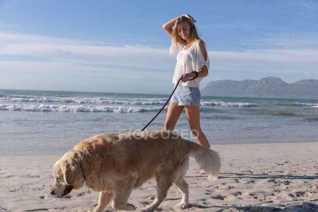 Кавказька жінка вигулювала собаку на пляжі. Здоровий вільний час на відкритому повітрі біля моря. — стокове фото
