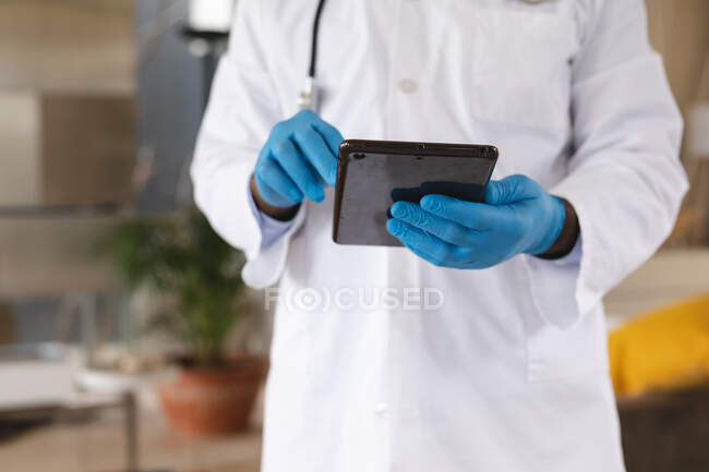 Mittlerer Abschnitt der männlichen Arzt mit digitaler Tablette zu Hause. Fernkommunikation und telemedizinisches Beratungskonzept. — Stockfoto