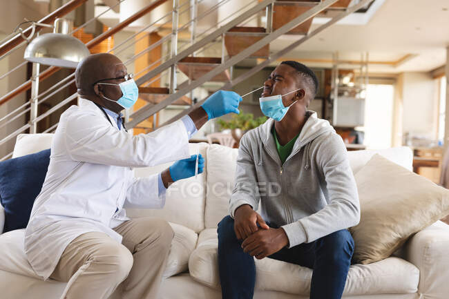 Лікар африканського походження, старший лікар - носовий суп-тест на африканського американця вдома. Медичні тести для запобігання спалаху коронавірусу — стокове фото