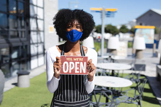 Африканська американка в масці з відкритим знаком. Незалежна кава, бізнес під час коронавірусної ковини 19 пандемії. — стокове фото
