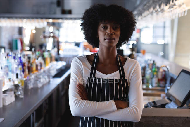 Retrato de uma barista afro-americana a usar avental a olhar para a câmara. café independente, pequeno negócio bem sucedido. — Fotografia de Stock
