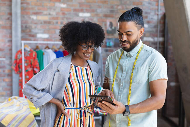 Smiling diverse male and female designers using tablet and talking. independent creative fashion design business. — Stock Photo