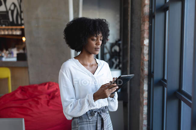 Afroamerikanerin steht, benutzt Tablet und arbeitet im Café. Digitale Kreative unterwegs. — Stockfoto