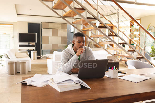 Afrikanischer junger Mann mit Laptop während seines Studiums zu Hause. Fernstudium und Online-Bildungskonzept — Stockfoto