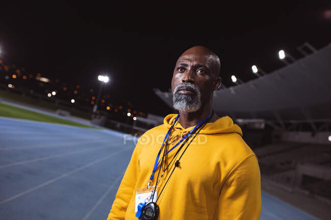 Afroamerikanischer Seniorentrainer, der nachts auf der Laufbahn steht. Konzept des paralympischen Sports — Stockfoto