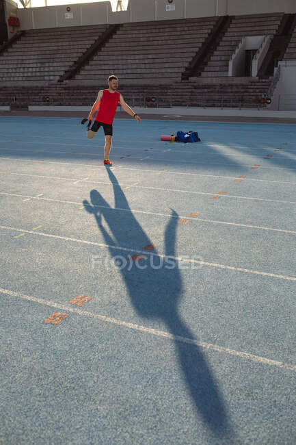 Кавказький спортсмен з протезом ноги виконує подовжену вправу на біговій доріжці. паралімпійська спортивна концепція — стокове фото