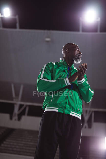 African american male coach clapping while standing on the running track at night. paralympic sport concept — Stock Photo