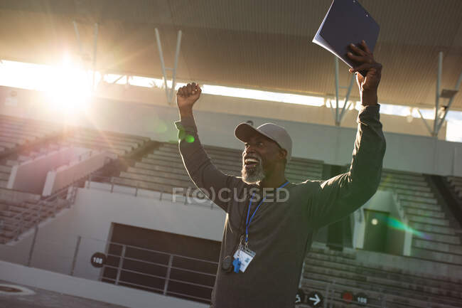 Treinador masculino afro-americano com prancheta torcendo na pista de corrida no estádio. conceito de esporte paralímpico — Fotografia de Stock