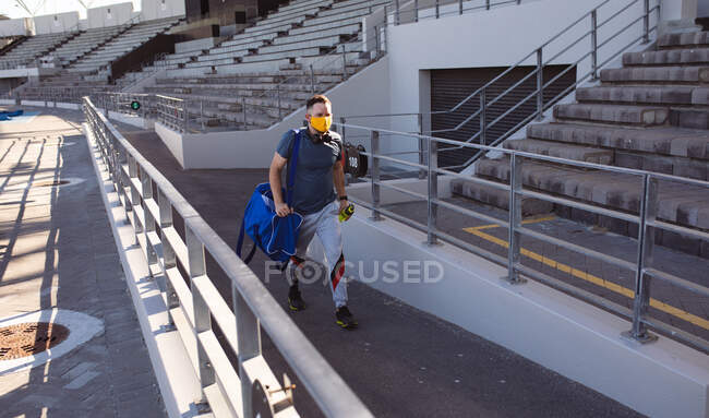 Kaukasischer männlicher Athlet mit Beinprothese und Gesichtsmaske beim Gehen im Stadion. paralympischer Sport und Covid-19-Epidemiekonzept — Stockfoto